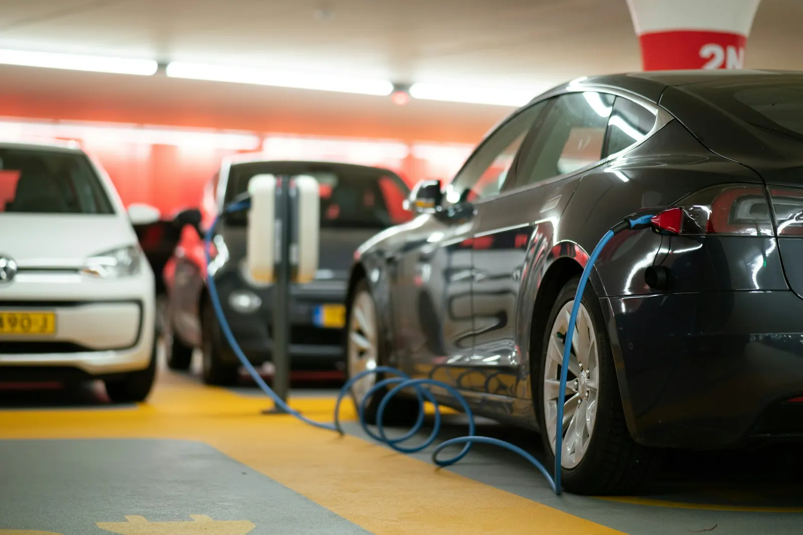 Mehrere Elektroautos an Ladestationen in einem Parkhaus